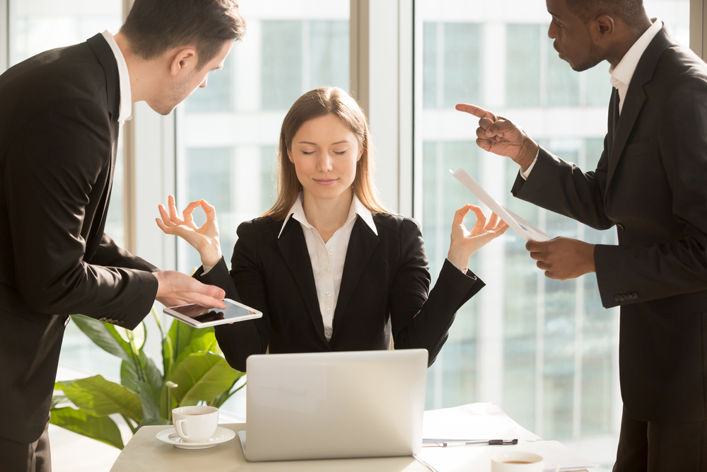 Woman Meditating in an office while 2 men try to distract her