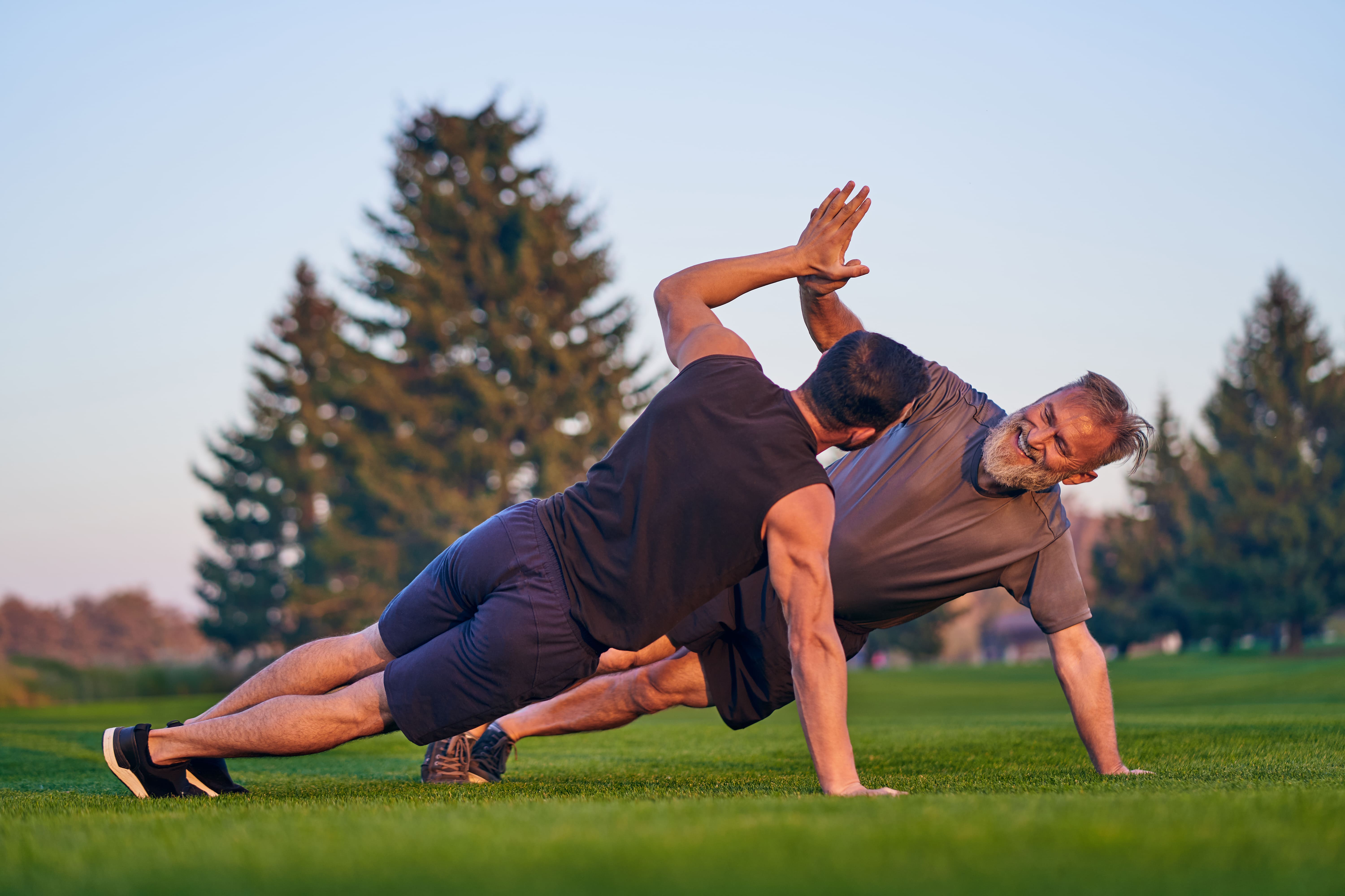 The Young And Old Men Push Up Together On The Grass